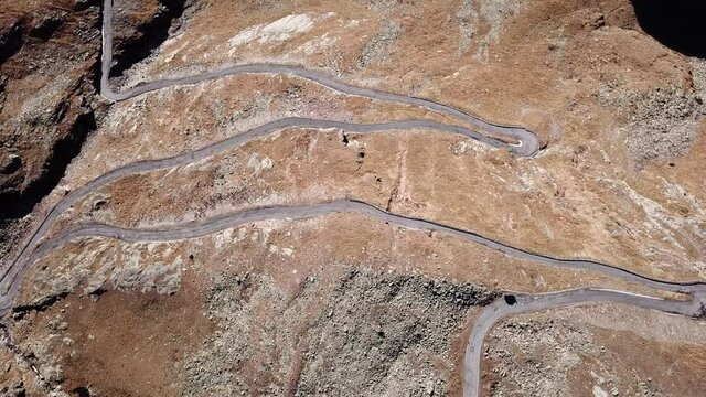 Road to the Gavia mountain pass in Italy. Up and down amazing aerial view of the mountain bends creating beautiful shapes. Fall time. Warm colors. Nobody on the road