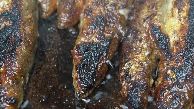 View of cooking frying capelin fish in iron pan. Grilled caplin fish - nutritious traditional unhealthy Asian dish