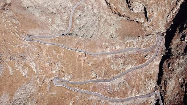 Road to the Gavia mountain pass in Italy. Up and down amazing aerial view of the mountain bends creating beautiful shapes. Fall time. Warm colors. Nobody on the road