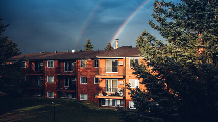Rainbow coming out from canadian red house during harsh sunlight with black background.