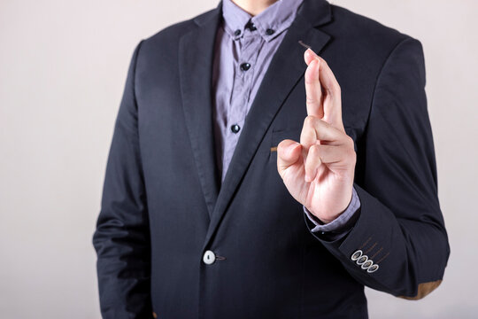 Man in business suit with fingers crossed, Represents the betrayal - Concept of corruption in work.