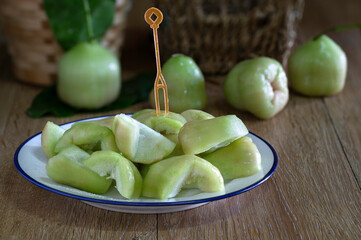Rose apples and cut sliced piece in white dish and on dark wooden table