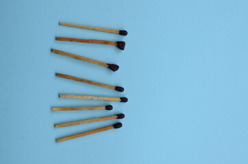 Scattered matches stick on a blue background with copyspace. Top view.
