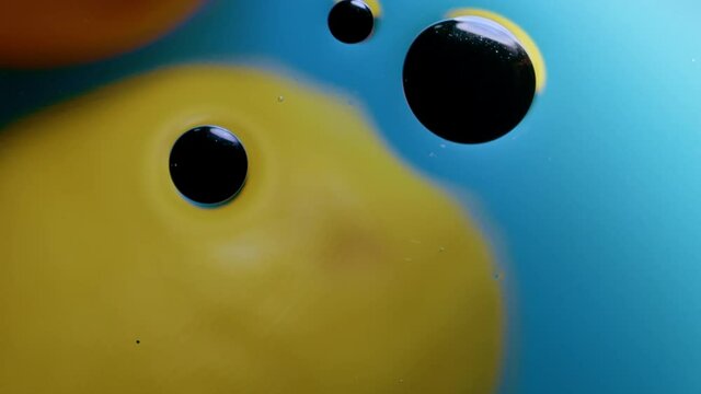 High quality abstract close-up 4k slow motion video of a bright colourful natural bacground with lemons and oranges giving orange blue and yellow colours with the water and oil bubbles moving around