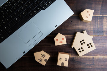 Wooden house, paper house and Laptop note book on wooden table background with copy space.Real...