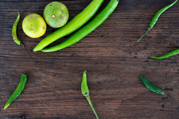 Food background with chili, lime, bell pepper placed on a wooden floor.