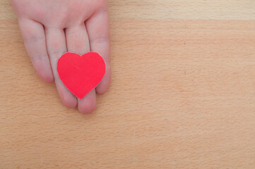 hand holding a red heart, health insurance, organ donor day, charity, foster family concept	