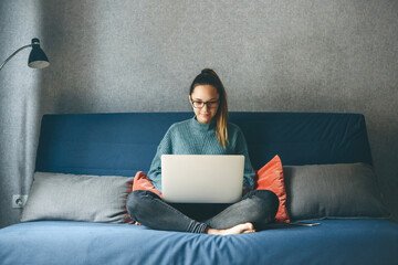 Girl working on laptop from home or student studying from home or freelancer. Or she is watching a video or using the Internet