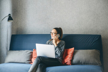 A girl works from home or a student is studying from home or a freelancer. She uses a laptop and a...