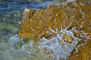 Splashing water against the background of stone and sea, water drops