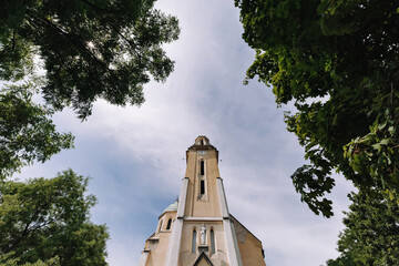 A church in Budapest, Hungary on a background of clouds and a frame with trees.