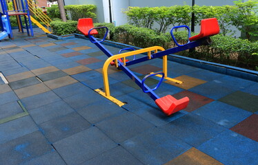 Closeup and selective focus on double seesaws installed on the same frame at silent playground with rubber block flooring 