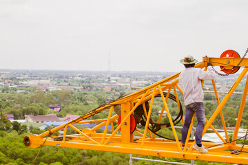 The technician removing tower crane from rooftop by derrick crane.