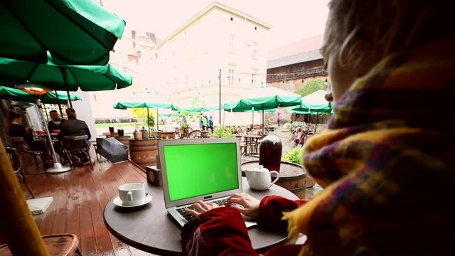 Young woman typing on laptop with chromakey green screen outdoor with rainy modern exterior on background. Internet connecting wifi 3G 5G. Online chatting communication app. Networking business people