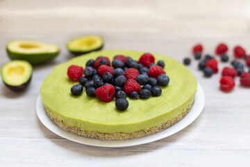 Tasty homemade avocado and lime Raw Cake with blueberries and raspberries, healthy vegan recipes