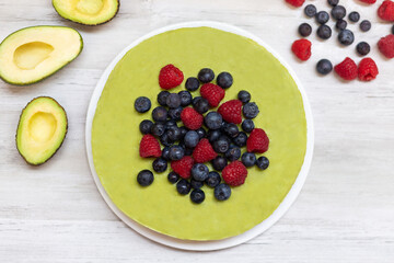 Tasty homemade avocado and lime Raw Cake with blueberries and raspberries, healthy vegan recipes