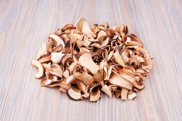 Edible dried mushrooms pile on light wooden background close up, dry boletus edulis heap on wood backdrop, chopped brown cap boletus, sliced penny bun, cep cut pieces, porcino, porcini, white fungus