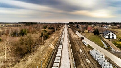 Zabiezki, Poland, 2020. Aerial view on railway line construction site in small village near Otwock and Warsaw. Railway components ready to deploy. Train tracks underlay and concrete ties.