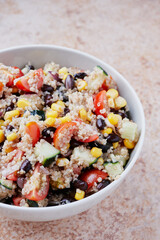 Healthy vegan quinoa bowl salad. Tomato, black beans, sweet corn and cucumber.
