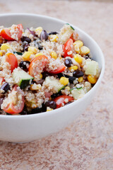 Healthy vegan quinoa bowl salad. Tomato, black beans, sweet corn and cucumber.