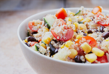 Healthy vegan quinoa bowl salad. Tomato, black beans, sweet corn and cucumber.