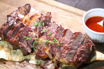 Delicious steak. Beef steak on wooden plate. Medium-roasted steak on a wooden board with sauce. 