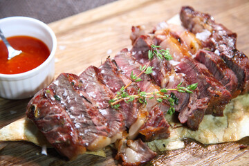 Delicious steak. Beef steak on wooden plate. Medium-roasted steak on a wooden board with sauce. 