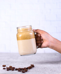 Dalgona coffee in a glass with dried coffee holding by hand