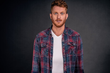 Fototapeta premium Waist-up shot of attractive masculine macho man with ginger hair in checkered shirt and gazing with confident and self-assured expression at camera, feeling calm and ready to work