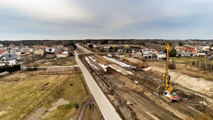 Zabiezki, Poland, 2020. Aerial view on railway line construction site in small village near Otwock and Warsaw. Railway components ready to deploy. Train tracks underlay and concrete ties.