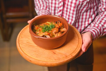 Traditional hot goulash soup. Waiter serving vegetable stew in a pot. Concept for a tasty meal. Restaurant service.