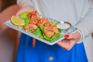Waiter serves grilled chicken meat with salad and sauce. Healthy dinner. Eating out in restaurant.