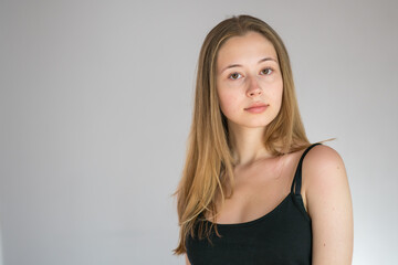 Obraz premium Portrait of an attractive teenage girl wearing a camisole posing looking at the camera on grey background