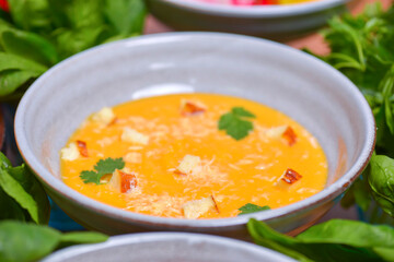 A bowl of spicy pumpkin soup, swirled with coconut cream.