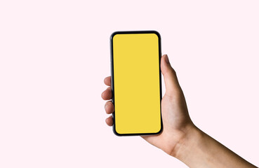 Hand holding white mobile phone with blank yellow screen in Light pink background.