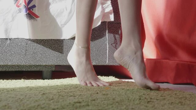 barefoot ballerina with bracelet on ankle dances near red cloth in sunny art studio with colorful drawings closeup slow motion