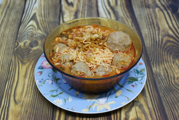 Indonesian traditional meatballs or bakso. Soup containing meatballs, noodles isolated on wood background