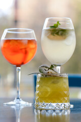 Three colorful refreshing cocktails served on a dark rustic wooden table with blurred background.