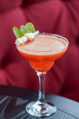 Cold summer alcohol cocktail with ice and fruit in a tall glass on light blurred restaurant or cafe background.