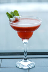 Cold summer alcohol cocktail with ice and fruit in a tall glass on light blurred restaurant or cafe background.