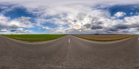 Full spherical seamless panorama 360 degrees angle view on no traffic asphalt road among fields with cloudy sky in equirectangular projection, VR AR content