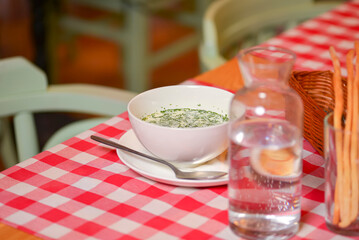 Okroshka. Summer light cold yogurt soup with cucumber, radish, eggs and dill in a bowl. Dinner in restaurant.