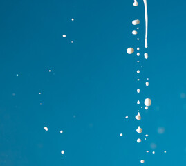 Splashes of white milk isolated on a blue background.