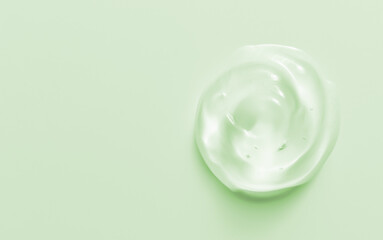 Cosmetic gel drop. Hand sanitizer, alcohol gel blob on pastel green background. Transparent cream swirl. Skin care product sample close up