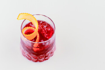 Cold summer alcohol cocktail with ice and orange in a small glass isolated on white background.