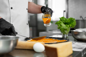 Cooking pizza. Close-up of the chef's hand pouring sauce over the pizza dough