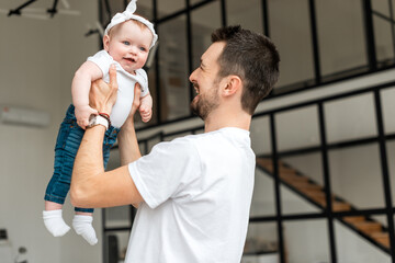 A young man hold her tiny daughter. Little girl smiling happily