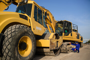 young man contractor builder in blue overalls is looking to the bulldozer wheel.