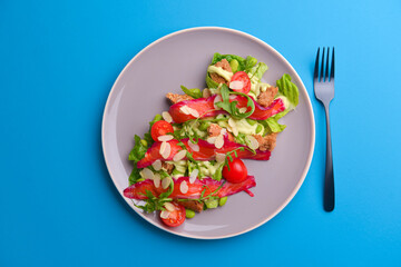 Fresh salad with smoked salted salmon, tomatoes and pumpkin seeds. Served on a gray plate over gray texture background.