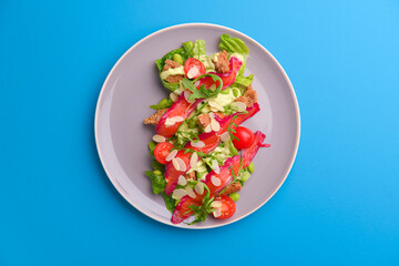Fresh salad with smoked salted salmon, tomatoes and pumpkin seeds. Served on a gray plate over gray texture background.